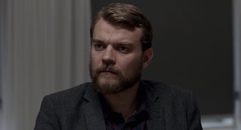Movie still from “A War” (2015), directed by Tobias Lindholm – A man with a beard wearing a suit and tie; Close Up shot, Over the shoulder angle