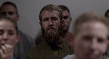 Movie still from “A War” (2015), directed by Tobias Lindholm – A man with a beard is looking at the camera; Close Up shot, Over the shoulder angle
