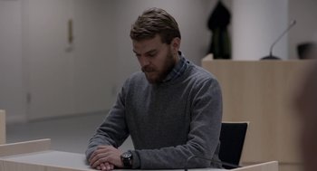 Movie still from “A War” (2015), directed by Tobias Lindholm – A man sitting at a table looking down at his watch; Medium shot, Over the shoulder angle