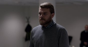 Movie still from “A War” (2015), directed by Tobias Lindholm – A man with a beard wearing a gray sweater; Medium shot, Over the shoulder angle