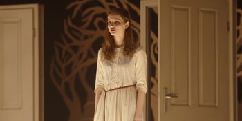Movie still from “Dark” (2017), created by Baran bo Odar – A woman in a white dress standing in front of a door; Medium shot, Low angle