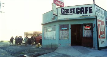 Movie still from “A Woman Under the Influence” (1974), directed by John Cassavetes – A couple of men standing outside of a store; Wide shot, Low angle