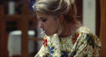 Movie still from “A Woman Under the Influence” (1974), directed by John Cassavetes – A woman is smoking a cigarette while wearing a dress; Close Up shot, Low angle