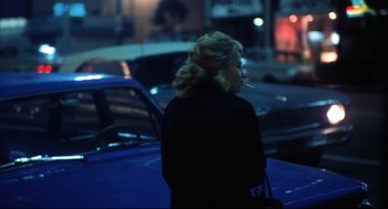 Movie still from “A Woman Under the Influence” (1974), directed by John Cassavetes – A woman standing on the side of the road smoking a cigarette; Medium shot, Over the shoulder angle