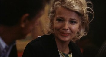 Movie still from “A Woman Under the Influence” (1974), directed by John Cassavetes – A woman with blonde hair is smiling for the camera; Close Up shot, Over the shoulder angle
