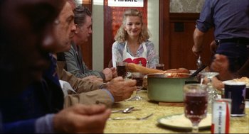 Movie still from “A Woman Under the Influence” (1974), directed by John Cassavetes – A group of people sitting around a table with food on top of it; Medium shot, Over the shoulder angle