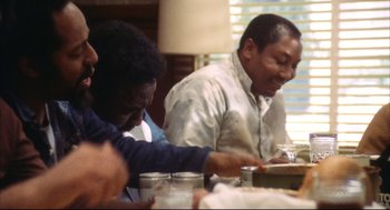 Movie still from “A Woman Under the Influence” (1974), directed by John Cassavetes – A group of people sitting at a table with food on it; Medium shot, Low angle