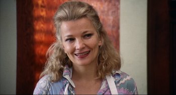 Movie still from “A Woman Under the Influence” (1974), directed by John Cassavetes – A woman with long blonde hair smiling for the camera; Close Up shot, Over the shoulder angle