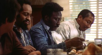 Movie still from “A Woman Under the Influence” (1974), directed by John Cassavetes – A group of people sitting at a table eating food; Medium shot, Low angle