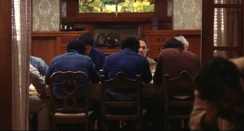 Movie still from “A Woman Under the Influence” (1974), directed by John Cassavetes – A group of people sitting around a table; Medium shot, Over the shoulder angle