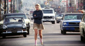 Movie still from “A Woman Under the Influence” (1974), directed by John Cassavetes – A woman crossing her arms on a busy city street; Wide shot, Low angle