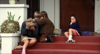 Movie still from “A Woman Under the Influence” (1974), directed by John Cassavetes – A group of children sitting on the steps of a house; Medium shot, Over the shoulder angle