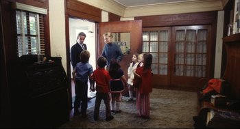 Movie still from “A Woman Under the Influence” (1974), directed by John Cassavetes – A group of children standing in front of an open door; Wide shot, High angle