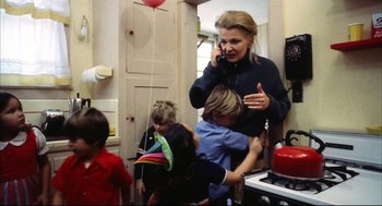 Movie still from “A Woman Under the Influence” (1974), directed by John Cassavetes – A woman talking on a phone while standing in a kitchen; Medium shot, High angle