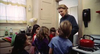 Movie still from “A Woman Under the Influence” (1974), directed by John Cassavetes – A group of children are gathered around an older woman; Medium shot, Over the shoulder angle
