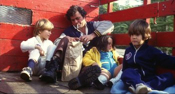 Movie still from “A Woman Under the Influence” (1974), directed by John Cassavetes – A group of children sitting on the ground with a man; Medium shot, High angle