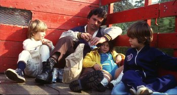 Movie still from “A Woman Under the Influence” (1974), directed by John Cassavetes – A group of people sitting next to each other on the ground; Medium shot, High angle