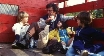 Movie still from “A Woman Under the Influence” (1974), directed by John Cassavetes – A group of people sitting next to each other on the ground; Medium shot, Low angle