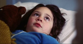 Movie still from “A Woman Under the Influence” (1974), directed by John Cassavetes – A little girl laying in a bed with a teddy bear; Close Up shot, High angle