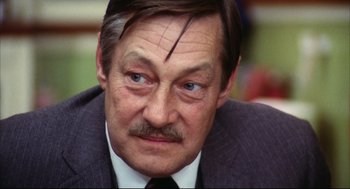 Movie still from “A Woman Under the Influence” (1974), directed by John Cassavetes – An older man wearing a suit and tie; Close Up shot, High angle