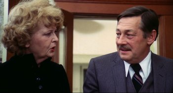 Movie still from “A Woman Under the Influence” (1974), directed by John Cassavetes – An older woman standing next to an older man in a suit; Close Up shot, Over the shoulder angle