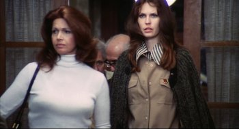 Movie still from “A Woman Under the Influence” (1974), directed by John Cassavetes – Two women are standing in a crowd of onlookers; Medium shot, Low angle