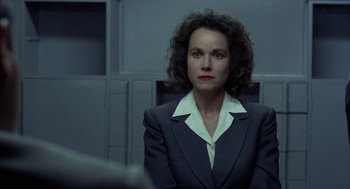 A woman wearing a suit and tie in a room