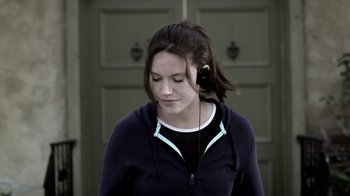 Movie still from “Absentia” (2011), directed by Mike Flanagan – A young woman wearing headphones while standing in front of a door; Close Up shot, Over the shoulder angle
