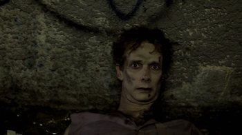 Movie still from “Absentia” (2011), directed by Mike Flanagan – A man with makeup on his face is looking at the camera; Close Up shot, Overhead angle