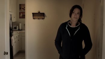 Movie still from “Absentia” (2011), directed by Mike Flanagan – A woman standing in front of a wall with her hands in her pockets; Medium shot, Over the shoulder angle