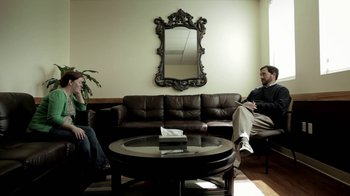 Movie still from “Absentia” (2011), directed by Mike Flanagan – Two people sitting on a couch in front of a mirror in a living room; Wide shot, Over the shoulder angle