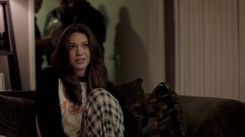 Movie still from “Absentia” (2011), directed by Mike Flanagan – A woman sitting on top of a couch in a living room; Medium shot, Over the shoulder angle