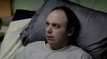 A man laying in a bed with his head on a pillow