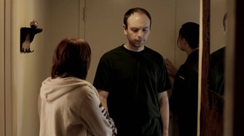 Movie still from “Absentia” (2011), directed by Mike Flanagan – A man standing in front of two women in front of a mirror; Medium shot, Over the shoulder angle