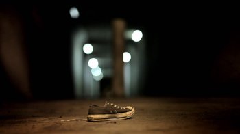 Movie still from “Absentia” (2011), directed by Mike Flanagan – A pair of tennis shoes sitting on the ground in front of lights; Wide shot, Low angle