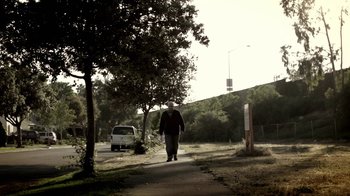 Movie still from “Absentia” (2011), directed by Mike Flanagan – A man walking down a sidewalk next to a tree; Wide shot, Low angle