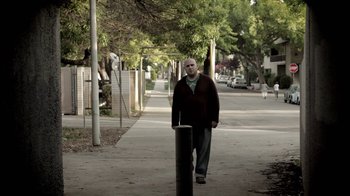 Movie still from “Absentia” (2011), directed by Mike Flanagan – A man walking down a sidewalk next to a pole; Wide shot, Low angle