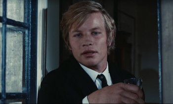 Movie still from “Accident” (1967), directed by Joseph Losey – A man in a suit and tie holding a glass; Close Up shot, Over the shoulder angle