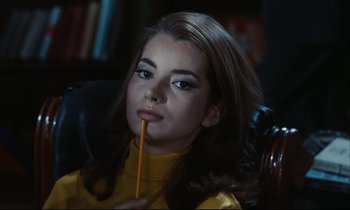 Movie still from “Accident” (1967), directed by Joseph Losey – A woman holding a pencil in her mouth while sitting in a chair; Close Up shot, High angle