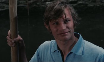 Movie still from “Accident” (1967), directed by Joseph Losey – A man in a blue shirt is smiling for the camera; Close Up shot, High angle