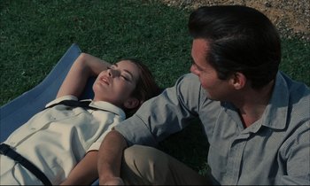 Movie still from “Accident” (1967), directed by Joseph Losey – A man and a woman laying in the grass; Medium shot, High angle