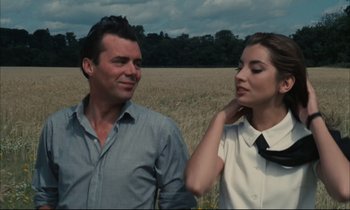 Movie still from “Accident” (1967), directed by Joseph Losey – A man and a woman standing next to each other in a field; Close Up shot, Low angle