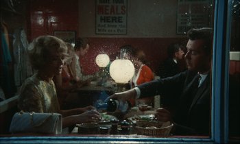 Movie still from “Accident” (1967), directed by Joseph Losey – A man is serving a woman at a restaurant; Medium shot, High angle