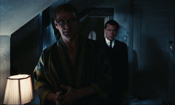 Movie still from “Accident” (1967), directed by Joseph Losey – A man in a striped robe standing next to another man in a suit; Medium shot, Low angle