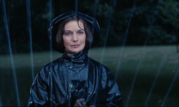 Movie still from “Accident” (1967), directed by Joseph Losey – A woman in a black raincoat standing in the rain; Close Up shot, Low angle