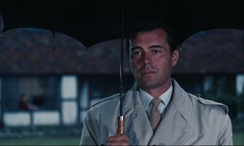 Movie still from “Accident” (1967), directed by Joseph Losey – A man holding an umbrella in the rain; Close Up shot, Low angle