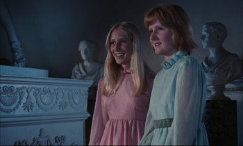 Movie still from “Accident” (1967), directed by Joseph Losey – Two young women standing next to each other in front of a statue; Medium shot, Low angle