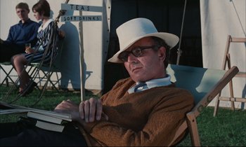Movie still from “Accident” (1967), directed by Joseph Losey – A man wearing a white hat sitting in a chair; Medium shot, Low angle