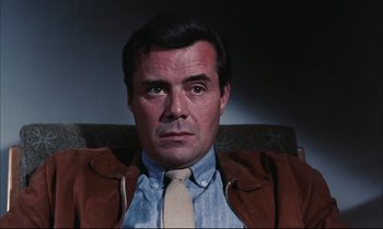 Movie still from “Accident” (1967), directed by Joseph Losey – A person wearing a jacket and a tie; Close Up shot, Low angle