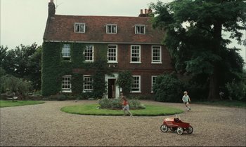 Movie still from “Accident” (1967), directed by Joseph Losey – Two children play in a yard with a toy car; Extreme Wide shot, High angle
